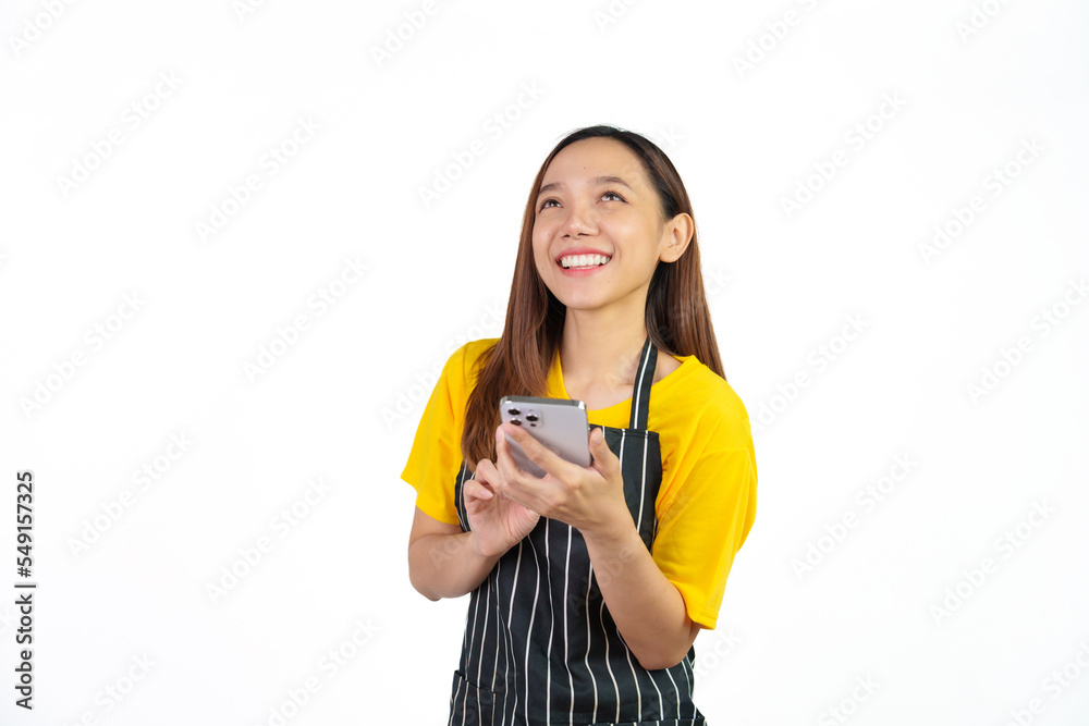 Texting on mobile to chat with customer, Portrait of confident asian woman barista and food owner shop with yellow t-shirt and black apron standing on white background.
