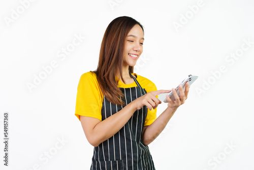 Received customer online order on mobile app, Portrait of confident asian woman barista and food owner shop with yellow t-shirt and black apron standing on white background.