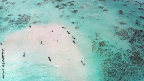 4K flying drone footage of boats on white sandbank coast with beautiful transparent rippled waves washing coral reefs atoll. Mnemba island, Zanzibar, Tanzania.Traveling in innocent Nature concept. photo