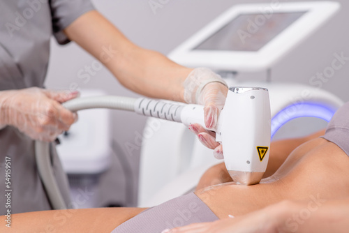 Professional beautician removes hair on beautiful female tummy using a laser. hair removal on the belly, laser procedure at clinic