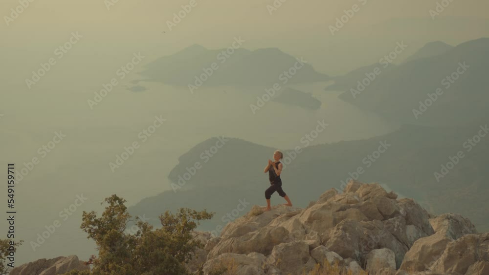 Athletic woman meditating. Silhouette of woman standing on top of mountain and practicing yoga Athletic woman meditating. Silhouette of woman standing on top of mountain and practicing yoga