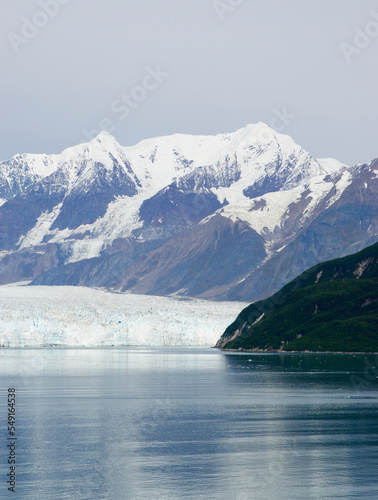 glacier at the water edge and snow capped mountains in the distance in alaska