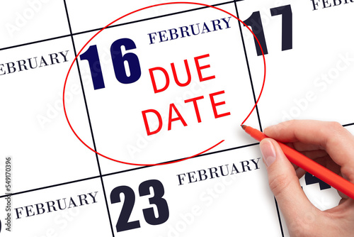 16th day of February. Hand writing text DUE DATE on calendar date February 16 and circling it. Payment due date. Business concept. Winter month, day of the year concept.