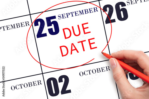 25th day of September. Hand writing text DUE DATE on calendar date September 25 and circling it. Payment due date. Business concept. Autumn month, day of the year concept.
