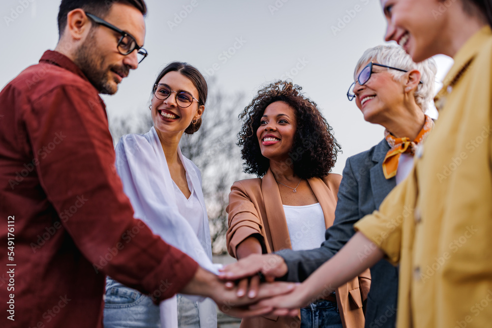 Obraz premium Business people putting hands in the middle, cheering to themselves.