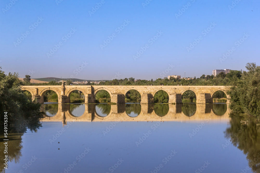 Ancient roman bridge across the Guadalquivir river in the morning tranquility at the medieval city of Cordoba, Andalusia. Spain