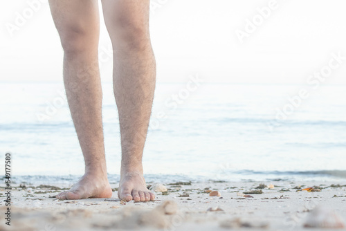 Barefoot male legs stand on the wet coastal sand on the shores of Puerto Progreso yucatan, mexico