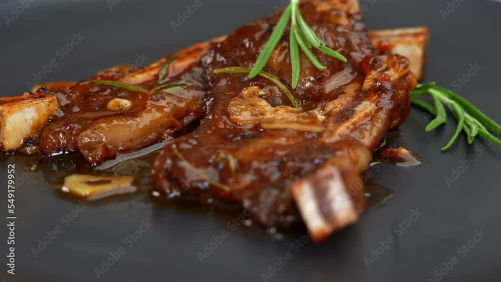 Fried steak beef ribs with garlic and rosemary, spices and seasonings rotate on plate