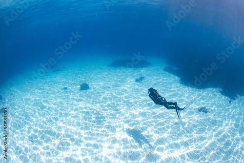 Women having fun underwater snorkeling in shallow clear waters with sunrays in the ocean