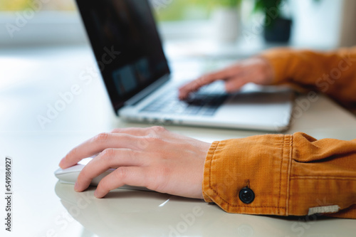Close-up woman searching and clicking mouse using laptop, online shopping concept. Blurred background