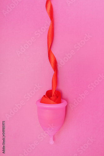 menstrual cup with red ribbon as female bleeding during menstruation, the concept of menstruation period, the female cycle