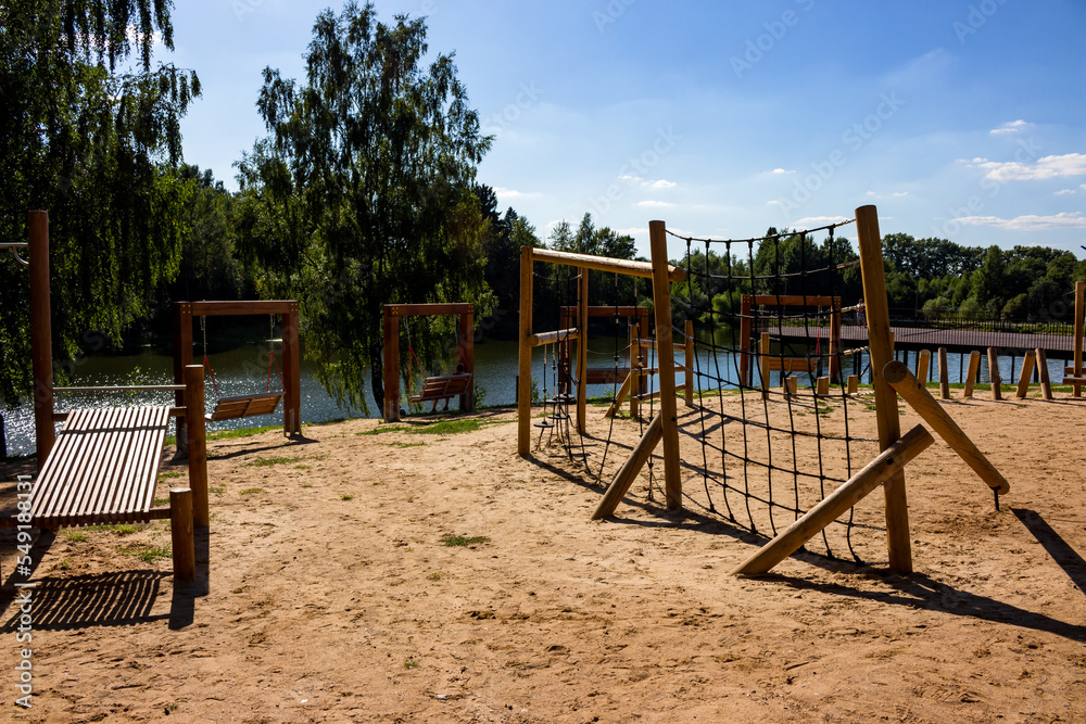 Children's sports and entertainment area built of wood on the beach near the pond