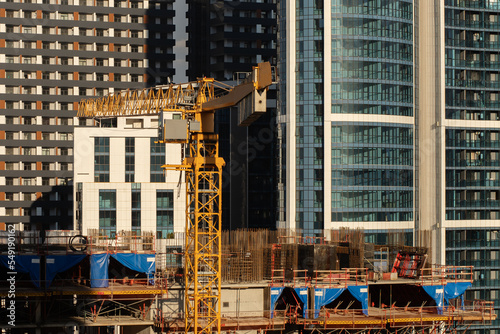 construction site, construction of a multi-storey building, rebar and concrete frame, top floor, construction crane on the background of skyscrapers