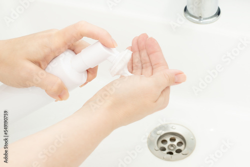 Facial skin care, cleanser face foam, Dispenser bottle in a woman's hand in bathroom
