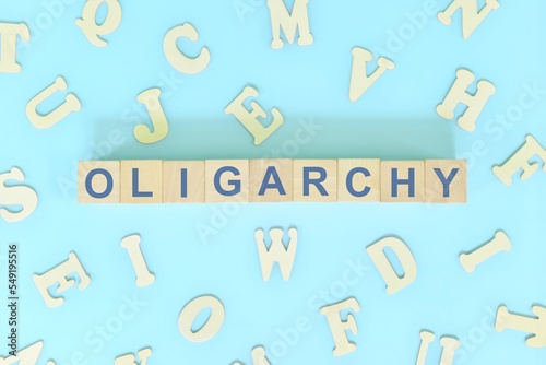 Oligarchy government form concept. Wooden blocks typography flat lay in blue background.	