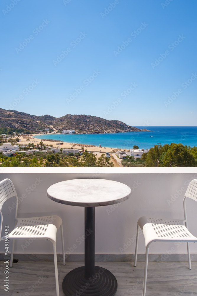 Amazing view from a balcony with chairs and a table overlooking the famous Mylopotas beach in Ios Greece
