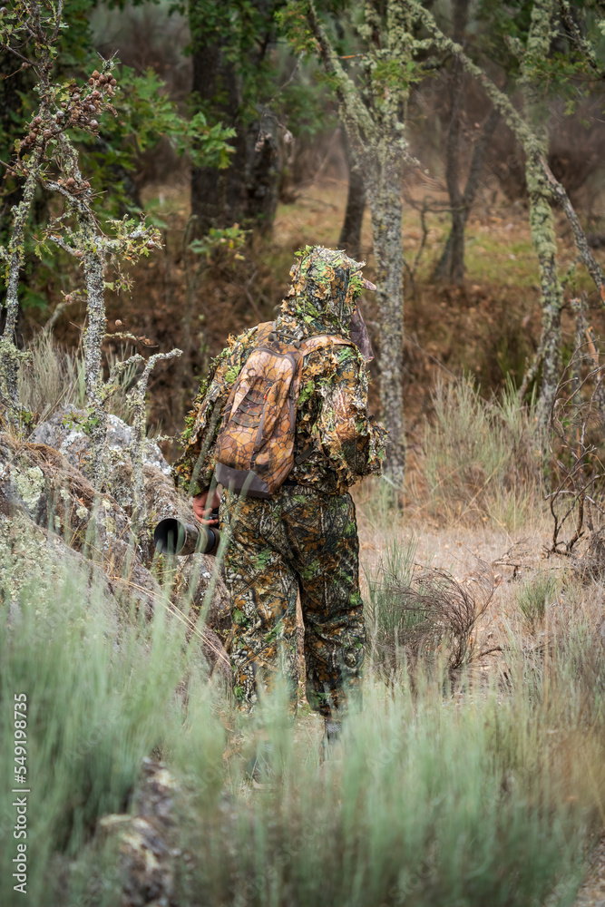 Photographer dressed in camouflage suit in the wild