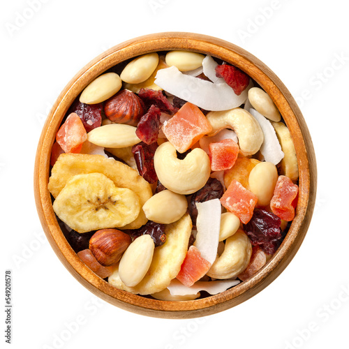 Exotic dried fruit mix with nuts, trail mix in a wooden bowl. Snack food and mixture of dried cranberries, banana chips, candied papaya, coconut chips, blanched almonds, hazelnut kernels and cashews.