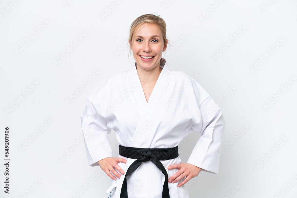 Young caucasian woman isolated on white background doing karate posing with arms at hip and smiling Young caucasian woman isolated on white background doing karate posing with arms at hip and smiling