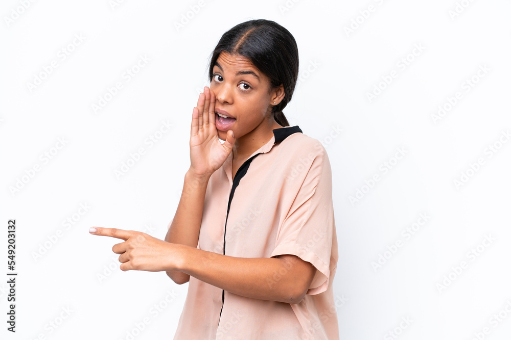 Young African american woman isolated on white background pointing to the side to present a product and whispering something Young African american woman isolated on white background pointing to the side to present a product and whispering something