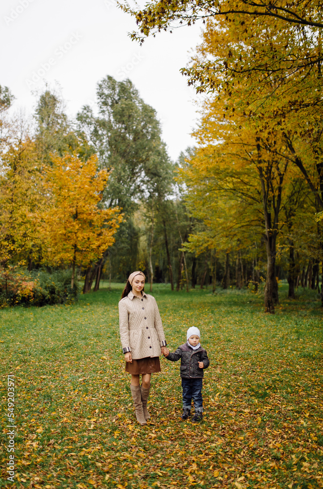 Fototapeta premium Mom and son walking and having fun together in the autumn park.