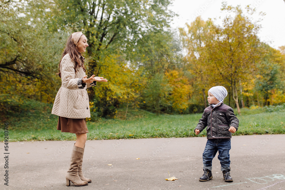 Fototapeta premium Mom and son walking and having fun together in the autumn park.