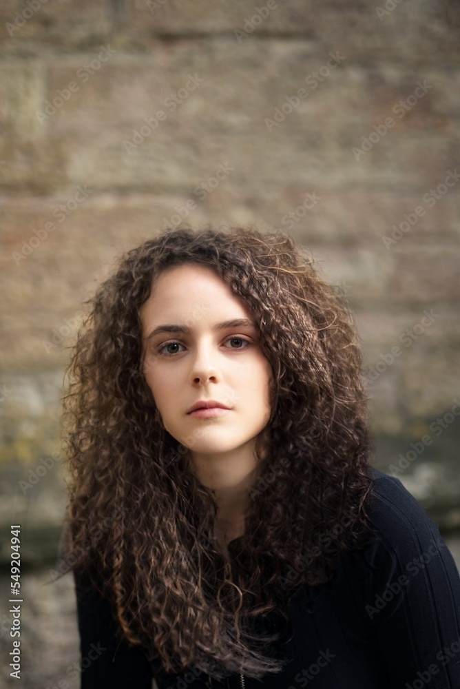A curly-haired beautiful girl against a stone wall A curly-haired beautiful girl against a stone wall