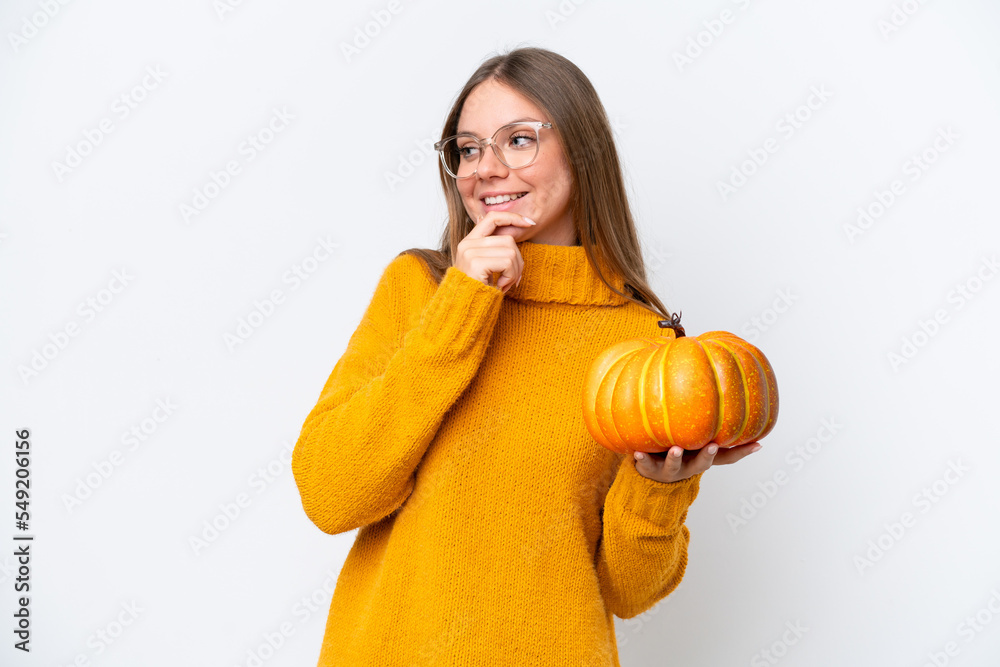 Young caucasian woman holding a pumpkin isolated on white background thinking an idea and looking side Young caucasian woman holding a pumpkin isolated on white background thinking an idea and looking side
