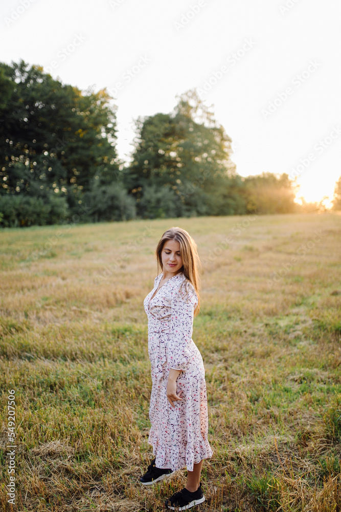 Young woman with beautiful hair posing in field at sunset. Fashion, independence Young woman with beautiful hair posing in field at sunset. Fashion, independence