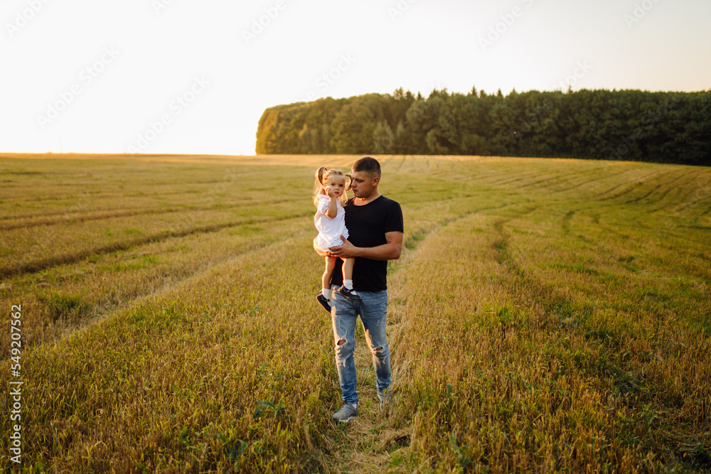 Happy family in a field in autumn. Mother, father and baby play in nature in the rays of sunset.