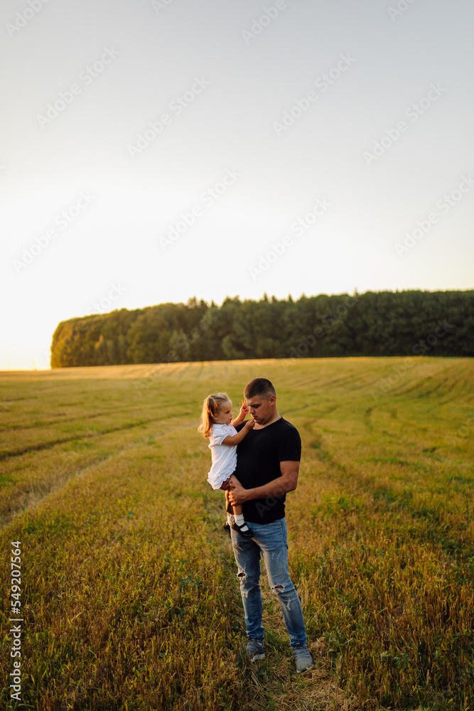 Happy family in a field in autumn. Mother, father and baby play in nature in the rays of sunset.