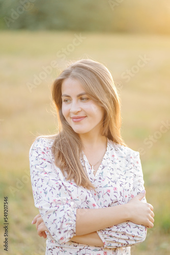 Young woman with beautiful hair posing in field at sunset. Fashion, independence