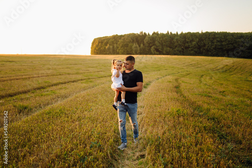 Happy family in a field in autumn. Mother, father and baby play in nature in the rays of sunset. © andriyyavor