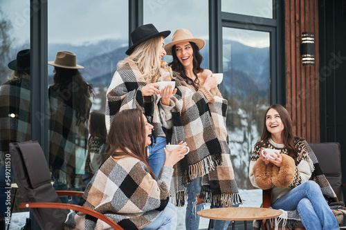 Canvas Print Young women enjoying winter weekends on terrace of contemporary barn house