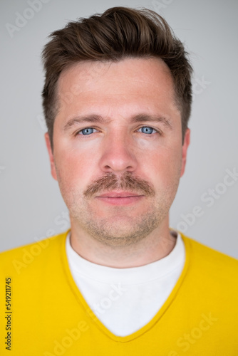 Passport picture of a guy in a checked shirt and pink t-shirt.
