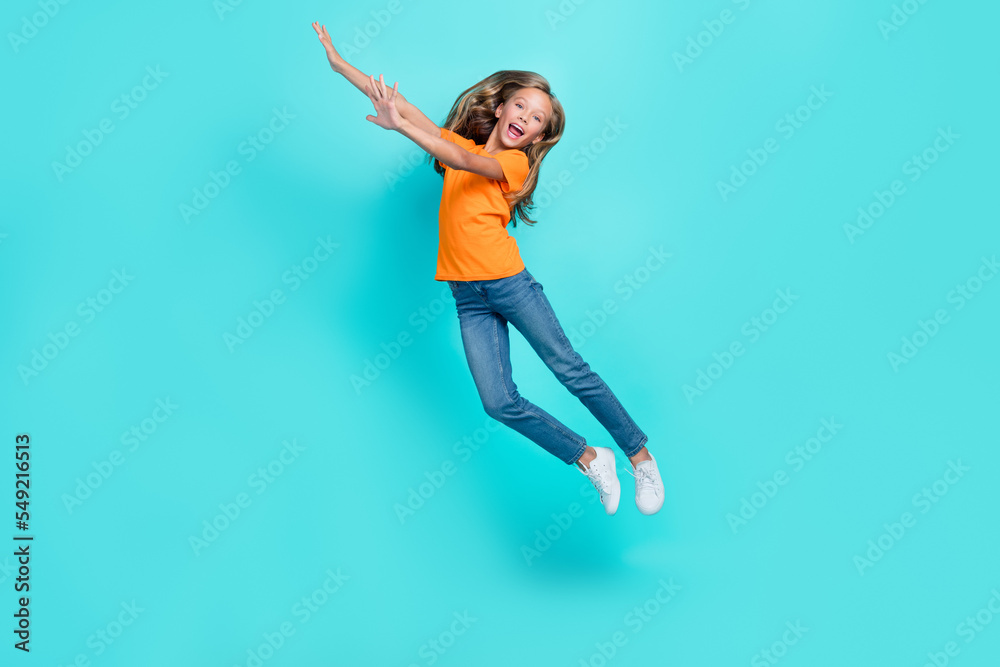 Full length photo of young funky cute schoolgirl blonde hair hands up jumping high trampoline celebrate her vacation time isolated on aquamarine color background