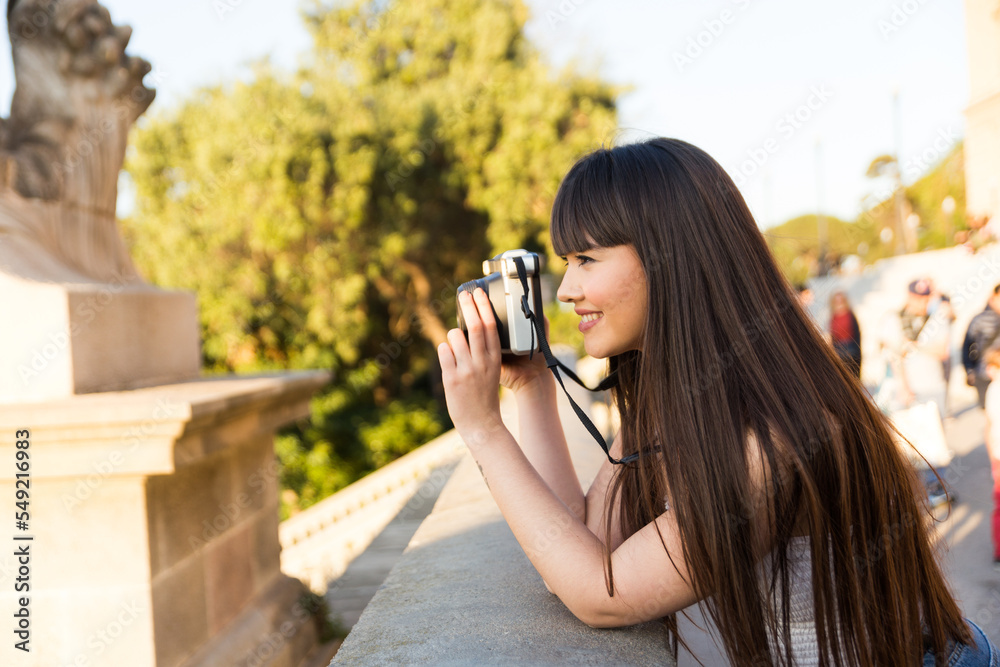 Young asian european woman doing sight seeing and smiling while she takes photos wih an old camera