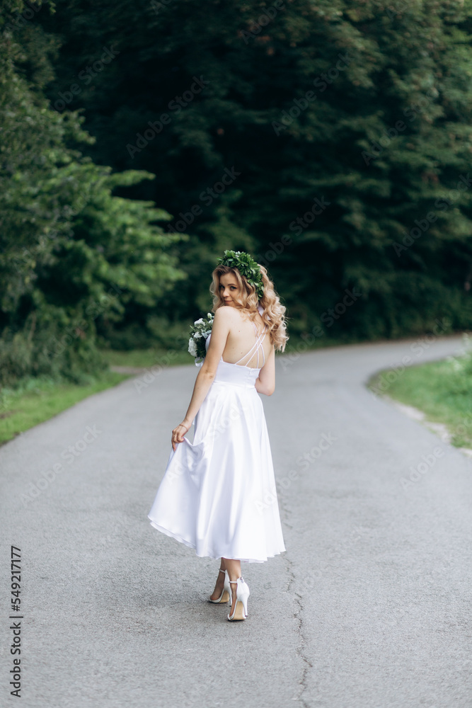 A happy young couple in love walk in a garden. A man in a white shirt and a girl in a white light dress are walking in a park A happy young couple in love walk in a garden. A man in a white shirt and a girl in a white light dress are walking in a park