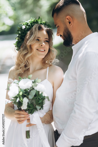 A happy young couple in love walk in a garden. A man in a white shirt and a girl in a white light dress are walking in a park