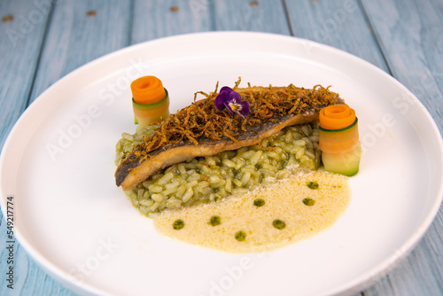 Recipe for fried fillet of sea bass with herb risotto, white wine sauce, fresch creme, roll of carrot and courgette strips, candied and fried lemon peel, High quality photo photo