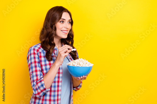 Photo of young funky girl wear checkered shirt unexpected moment movie interested look mockup eat popcorn isolated on yellow color background