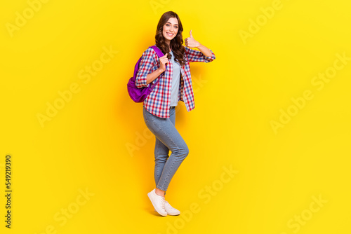 Full length photo of young woman stay okey showing like symbol hold backpack walk from university courses isolated on yellow color background