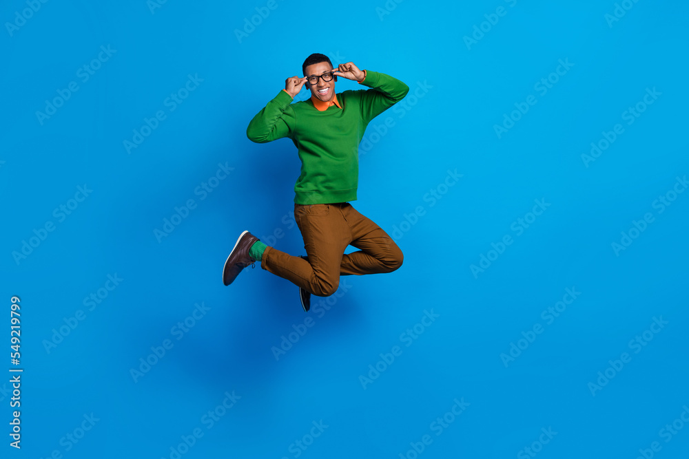 Obraz premium Full body length photo of young excited positive gentleman guy jumping air hold his eyeglasses celebrate weekend isolated on blue color background