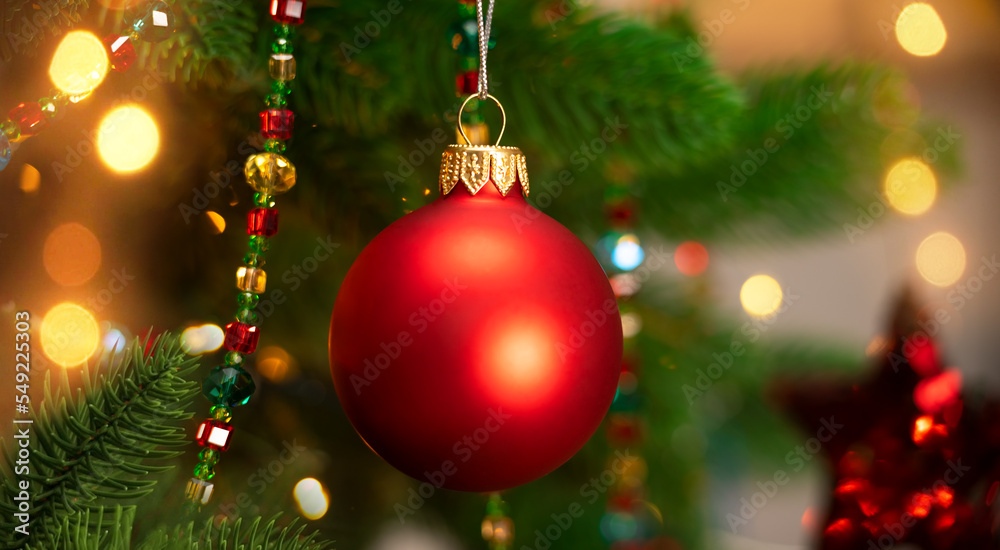 Red ball of Christmas tree on background of garland. Christmas New Year
