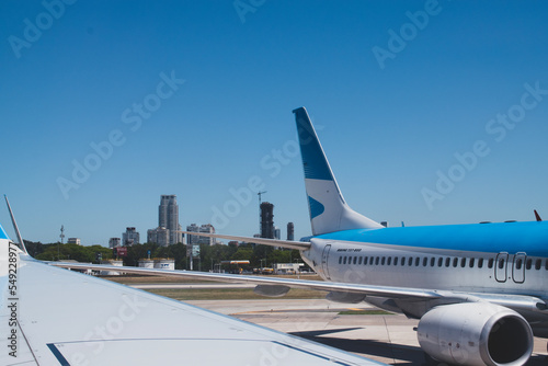 The tail end of a large airplane, parked at the gate, with the city of Buenos Aires in the background. 