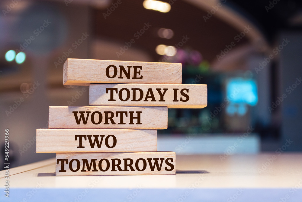 Wooden blocks with words 'One today is worth two tomorrows'.