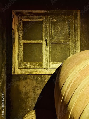 Fotografie Old cellar with illuminated retro window and oak barrel in a winery
