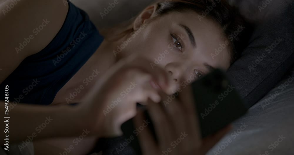 Young woman using phone in bed at night Young woman using phone in bed at night