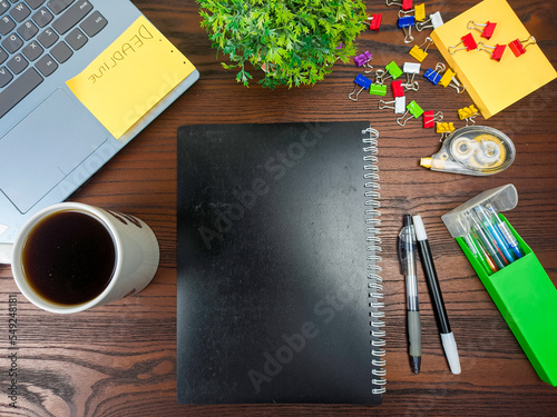 Flat lay, a mockup of a notebook. A workspace with white notebooks, laptops, office supplies, pencils, and coffee cups in the office background of a wooden desk from top view. photo