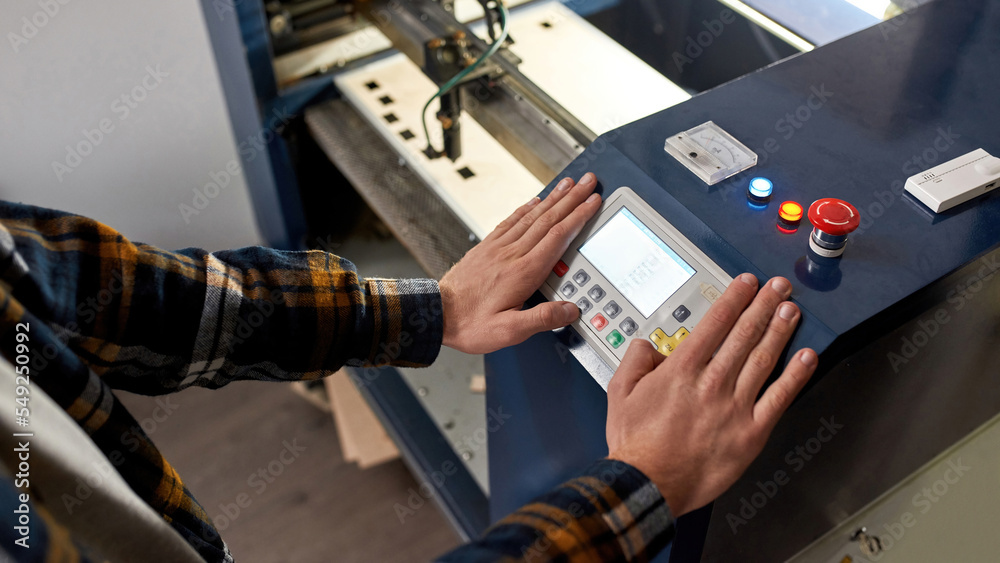 Cropped male worker pressing button on CNC machine Cropped male worker pressing button on CNC machine